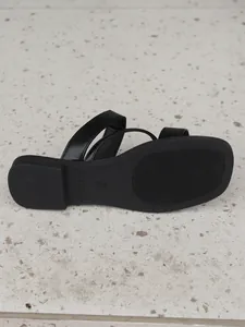 Detail view of black flat sandal sole with retro square toe and minimalist straps