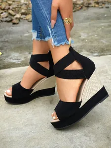 Close-up of black suede wedge sandals with elastic straps and woven platform detail.
