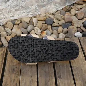 Detailed macro view of the non-slip black rubber outsole of the women's flat slipper.