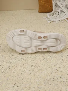 Detail view of beige fly-knit flat slipper showing non-slip textured rubber outsole