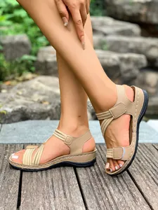 Detail of women's beige sports sandals with elastic straps and velcro on a wooden deck