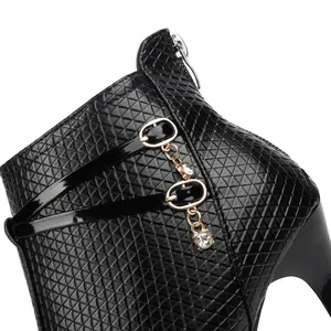 Close-up of black stiletto boot with geometric texture and rhinestone chain detail.