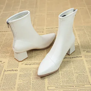 Elegante weiße Stiefeletten mit Blockabsatz und spitzer Kappe auf Vintage-Zeitung