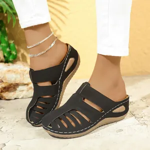 Detailansicht schwarzer Pantoletten mit Cut-out-Design und weißen Kontrastnähten