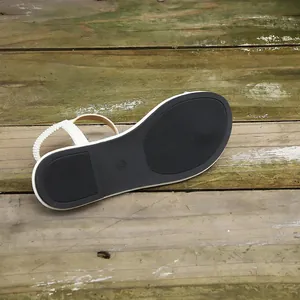 Detailed view of the durable non-slip black sole and white elastic heel strap of the sandal.