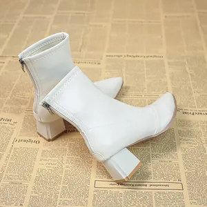 Nahaufnahme von weißen Stiefeletten mit Blockabsatz auf Vintage-Zeitungs-Hintergrund