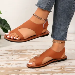 Primo piano di sandali da spiaggia piatti marroni con velcro e design ad anello.