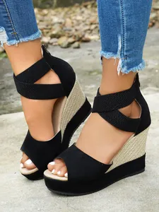 Detail view of black suede wedge sandals with woven platform and elastic straps