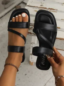 Close-up of black retro flat sandals with square toe and asymmetric straps