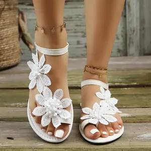 Detail of white toe-ring flat sandals with elegant lace floral decorations for beach