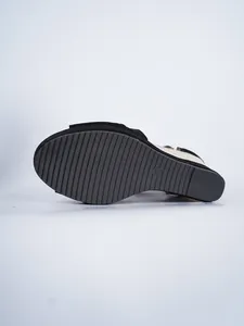 Detailed view of the grooved rubber sole and straw wedge on black suede sandals