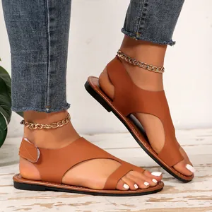 Vista dettagliata di sandali marroni bassi da donna con cinturino in velcro e cavigliera