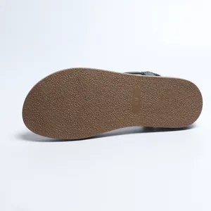 Detail view of the textured non-slip brown sole of a women's flat Roman sandal