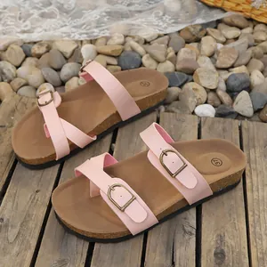 Close-up of pink women's flat slippers with adjustable metal buckles on wooden planks