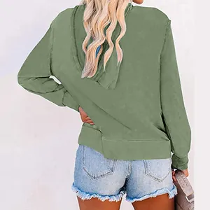 Back view of a casual women's sage green long sleeve hoodie paired with denim shorts