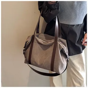 Una persona que lleva un gran bolso de viaje de lona caqui con asas de cuero marrón
