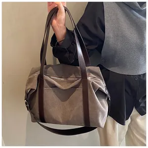 Bolso tote grande de lona gris con asas marrones sostenuto por una persona.