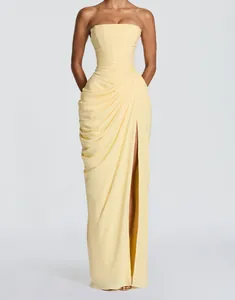 Elegant pale yellow strapless evening gown featuring asymmetric draping and a high leg slit.