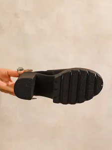 Detailed view of the anti-slip grooved outsole and chunky high heel of a black boot