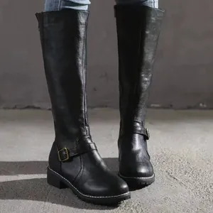 Detail view of women's black leather rider boots with buckle and sturdy lug sole.
