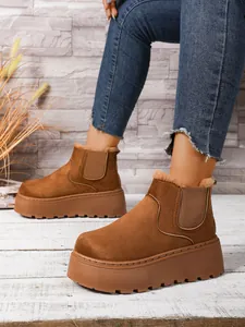 Detail of brown suede snow boots with chunky platform sole and warm interior lining.