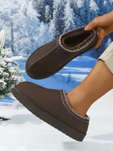 Vista detallada de botas de nieve marrones con forro de felpa en un paisaje nevado