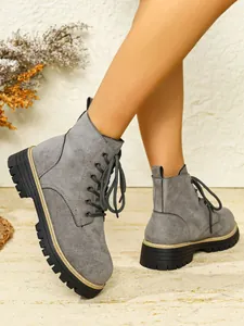 Nahaufnahme von eleganten grauen Wildleder-Stiefeletten mit robuster Plateau-Profilsohle