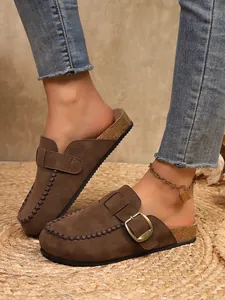 Close-up view of women's retro brown suede platform clogs with buckle and cork sole detail
