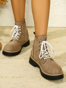 Nahaufnahme von stylischen braunen Wildleder-Stiefeletten mit dicken schwarzen Plateausohlen.