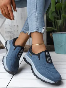 Détail de baskets d'extérieur bleues à semelles épaisses sur un parquet blanc.