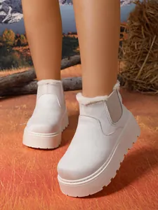 Close-up of white suede platform snow boots with warm faux fur lining on a model.