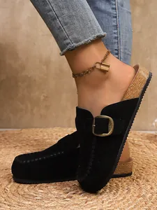 Detail of black suede retro thick sole loafers with gold buckle and cork style sole.
