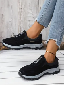 Détail de baskets outdoor noires avec semelles grises épaisses portées avec un jean