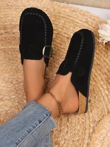 Detailed view of women's vintage black suede clogs with gold buckle and cork sole