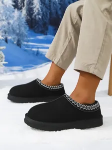 Detalle de botas de nieve negras para hombre con bordado y forro polar cálido.