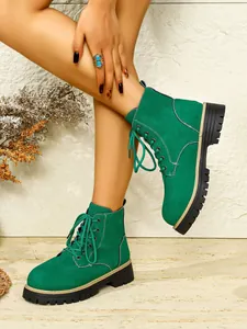 Nahaufnahme der grünen Wildleder-Stiefeletten für Damen mit dicken Profilsohlen.