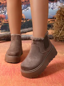 Close-up of brown suede platform snow boots with faux fur lining on model's feet