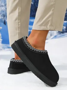 Detalle de botas de nieve negras para hombre con borde tejido en un entorno nevado
