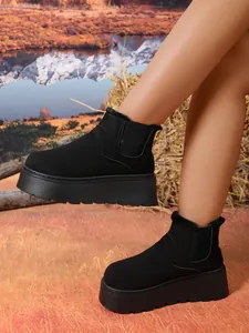 Close-up of black suede platform ankle snow boots featuring warm faux fur lining and elastic side