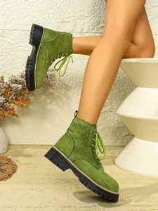 Detailansicht grüner Wildleder-Stiefeletten mit dicker Profilsohle und Schnürung vorne.
