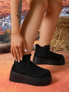 Side detail of women's black suede snow boots featuring thick platform soles and fur lining