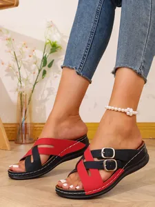 Detail view of women's red and black crisscross wedge sandals with buckle accents