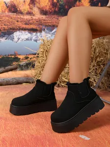 Detail view of stylish warm black suede platform snow boots on model for winter season