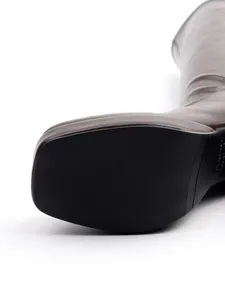 Macro detail of a square-toe knight boot showing non-slip rubber sole and premium brown leather