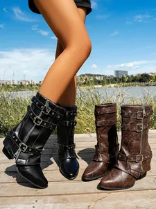 Detail view of women's mid-calf boots with multiple buckle straps in outdoor setting