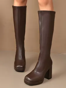Detailed view of elegant brown platform knee-high boots with block heels and square toes.