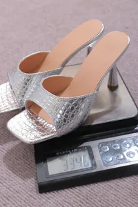 Silver square-toe high-heel mules with stone pattern displayed on weight scale