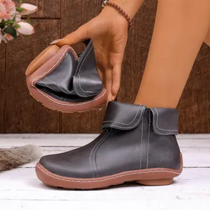 Flexible graue Lederstiefeletten, die die Weichheit der Sohle und weiße Nähte zeigen