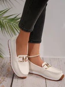 Detailed view of elegant white platform loafers with chic gold metal chain buckle