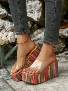 Detail of colorful striped wedge sandals with clear PVC straps and high platform heels.